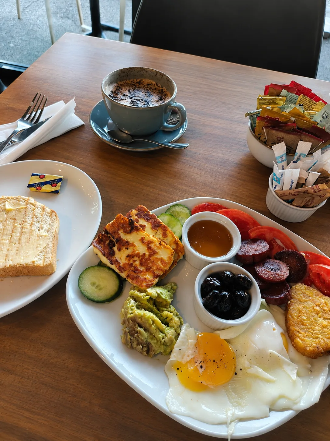 The Isla Bay Breakfast: grilled halloumi, Turkish sausage, olives, honey, avocado, tomato, cucumber, hash brown and fried eggs, with a cappuccino